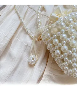 Detailed view of woven pearl bucket bag with satin bow and pearl chain strap