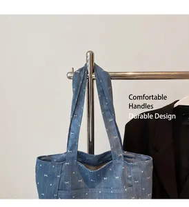 Close-up of blue denim tote bag with white bow pattern and reinforced wide handles