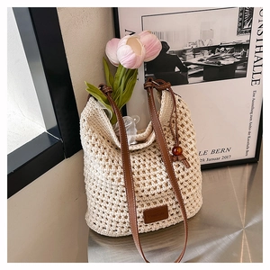 Détail du sac cabas crème tissé à la main avec bandoulière en cuir brun et logo