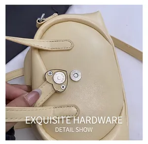 Detail of silver heart-shaped metal lock on cream-colored lychee textured leather bag