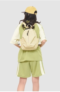 Détail d'un petit sac à dos en nylon crème porté par un mannequin montrant la taille