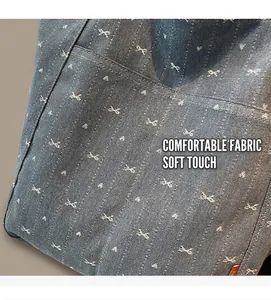 Close-up of blue denim tote bag with white bow pattern and side pocket detail