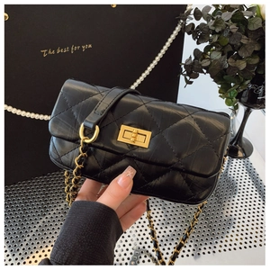 Détail d'un sac à chaîne matelassé noir avec fermoir tournant doré et bandoulière en cuir