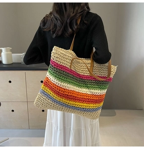 Detail of colorful rainbow woven straw tote bag with brown leather handles for summer beach