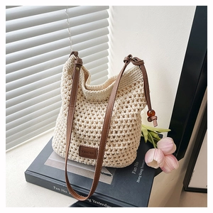 Détail du sac cabas crème tissé main avec étiquette en cuir marron et sangle perlée