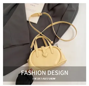 Detail of light yellow PU leather pillow bag with heart-shaped lock and shoulder strap