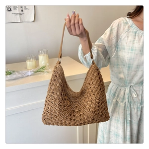 Close-up of lightweight woven straw tote bag with brown faux leather strap and metal buckle