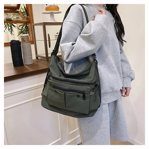 Detail of dark green nylon tote bag with multiple zipper compartments and adjustable strap