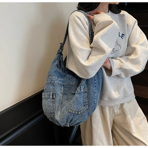 Detail view of large blue denim hobo bag with external pockets worn by a model