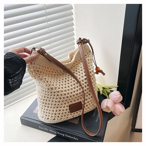 Détail d'un sac cabas en crochet beige fait main avec bandoulière en cuir et étiquette logo
