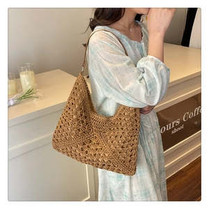 Close-up of woven straw tote bag featuring intricate hollow lace patterns and leather strap