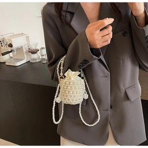 Close-up of pearl woven bucket bag with satin drawstring pouch and shoulder strap