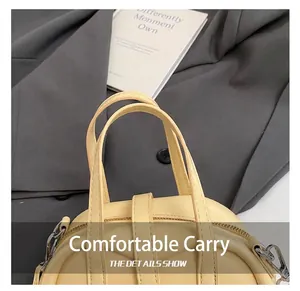 Detail of pale yellow handbag showing double handles and stitching with metal zipper