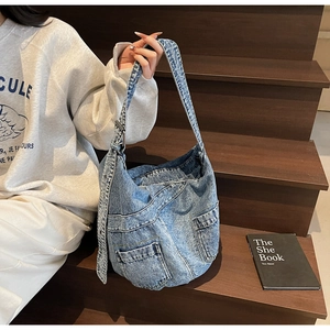 Detail of blue denim crossbody bag featuring multiple pockets and adjustable wide strap