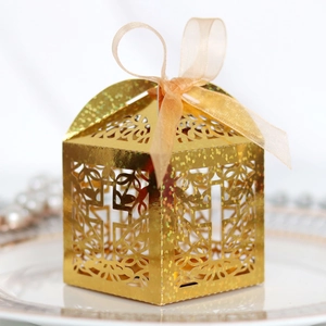 Detail of laser-cut cross on golden glitter favor box with elegant orange ribbon bow