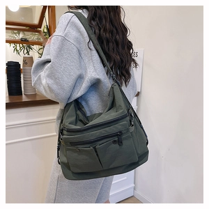 Detail of dark green multi-pocket nylon tote bag showing durable material and pockets