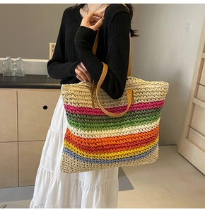 Close-up of colorful striped woven tote bag with brown leather handles worn by a model