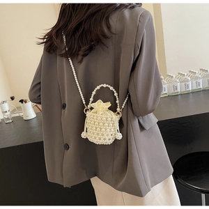 Detail shot of a woven pearl bucket bag with drawstring satin lining and crossbody strap