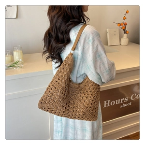 Detail of hollow-out hand-woven pattern and leather shoulder strap on brown hobo bag
