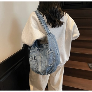 Detail of blue denim crossbody bag featuring vintage style and dual front pockets