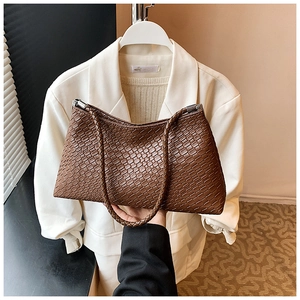 Détail de la texture tissée marron sur le sac d'épaule avec deux poignées tressées