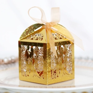 Detail of gold laser-cut wedding candy box with Mr & Mrs silhouette and champagne ribbon
