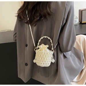 Detailed shot of a white woven pearl bucket bag with drawstring inner pouch and long strap