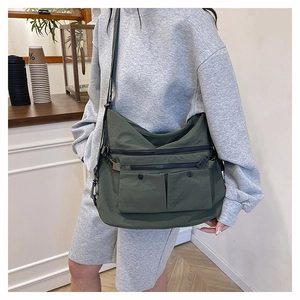 Detail view of large dark green nylon tote bag with multiple zippers and adjustable strap