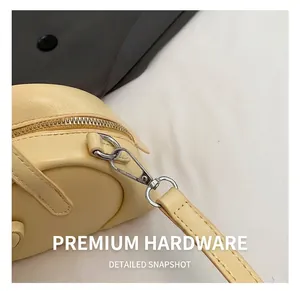 Macro shot of silver lobster clasp and leather strap detail on cream pillow bag