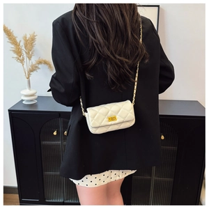 Détail d'un sac matelassé blanc avec fermoir doré et bandoulière en cuir et chaîne