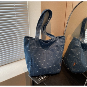 Detail of dark blue denim tote bag featuring white bow patterns and external pocket