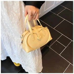 Detail of yellow pillow bag featuring heart-shaped ornament and soft faux leather texture