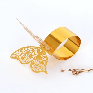 Detail of laser-cut gold butterfly napkin ring with intricate hollow heart patterns