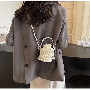 Detail of elegant hand-woven pearl bucket bag with drawstring closure and crossbody strap