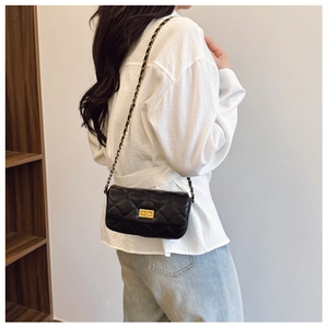 Détail d'un sac bandoulière noir en cuir matelassé avec chaîne dorée sur mannequin