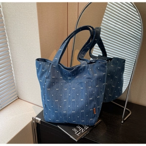 Detailed close-up of blue denim tote bag with white bow and heart embroidery details