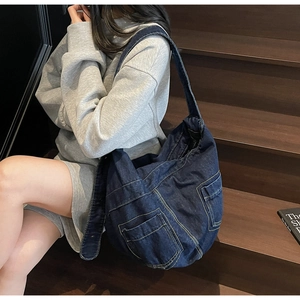 Detail of dark blue denim hobo bag with contrast yellow stitching and large pockets