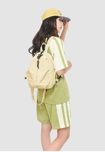 Vue latérale d'un sac à dos en toile beige sur modèle avec cordons noirs et poches latérales