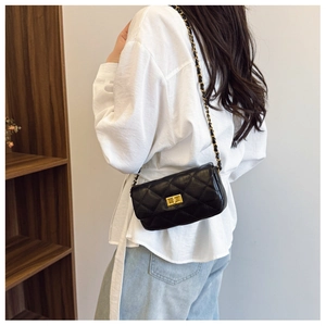 Détail d'un sac bandoulière matelassé noir avec chaîne dorée et fermoir rotatif métallique