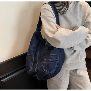 Close-up of large denim hobo bag with contrast stitching and dual front utility pockets