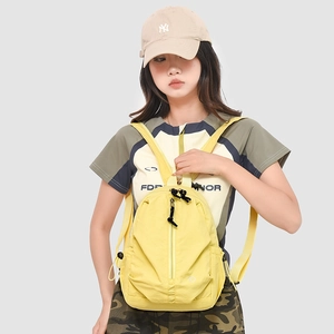 Détail d'un mini sac à dos jaune en nylon avec fermeture éclair verticale et logo rond