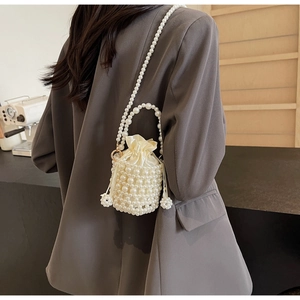 Detail of woven pearl bucket bag with cream satin drawstring lining and luxury handle