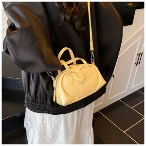 Cream crossbody pillow bag with 3D heart detail shown on a model for size perspective