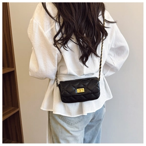 Détail d'un sac à bandoulière en cuir noir matelassé avec chaîne dorée et fermoir