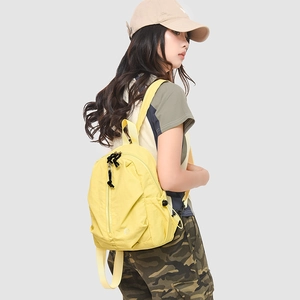 Détail du sac à dos en nylon jaune avec fermetures éclair noires et poches latérales souples