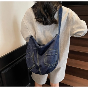 Detailed view of spacious navy denim crossbody bag with dual pocket design features