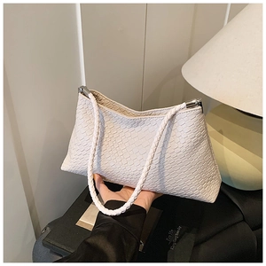 Détail de la texture en cuir tressé blanc d'un sac à bandoulière avec finitions argentées