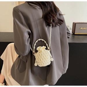 Detailed view of white woven pearl bucket bag with silk drawstring and chain strap