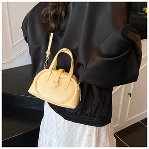 Close-up of light yellow mini handbag featuring a heart-shaped buckle and crossbody strap