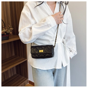 Modèle portant un sac bandoulière matelassé noir avec chaîne dorée et fermoir